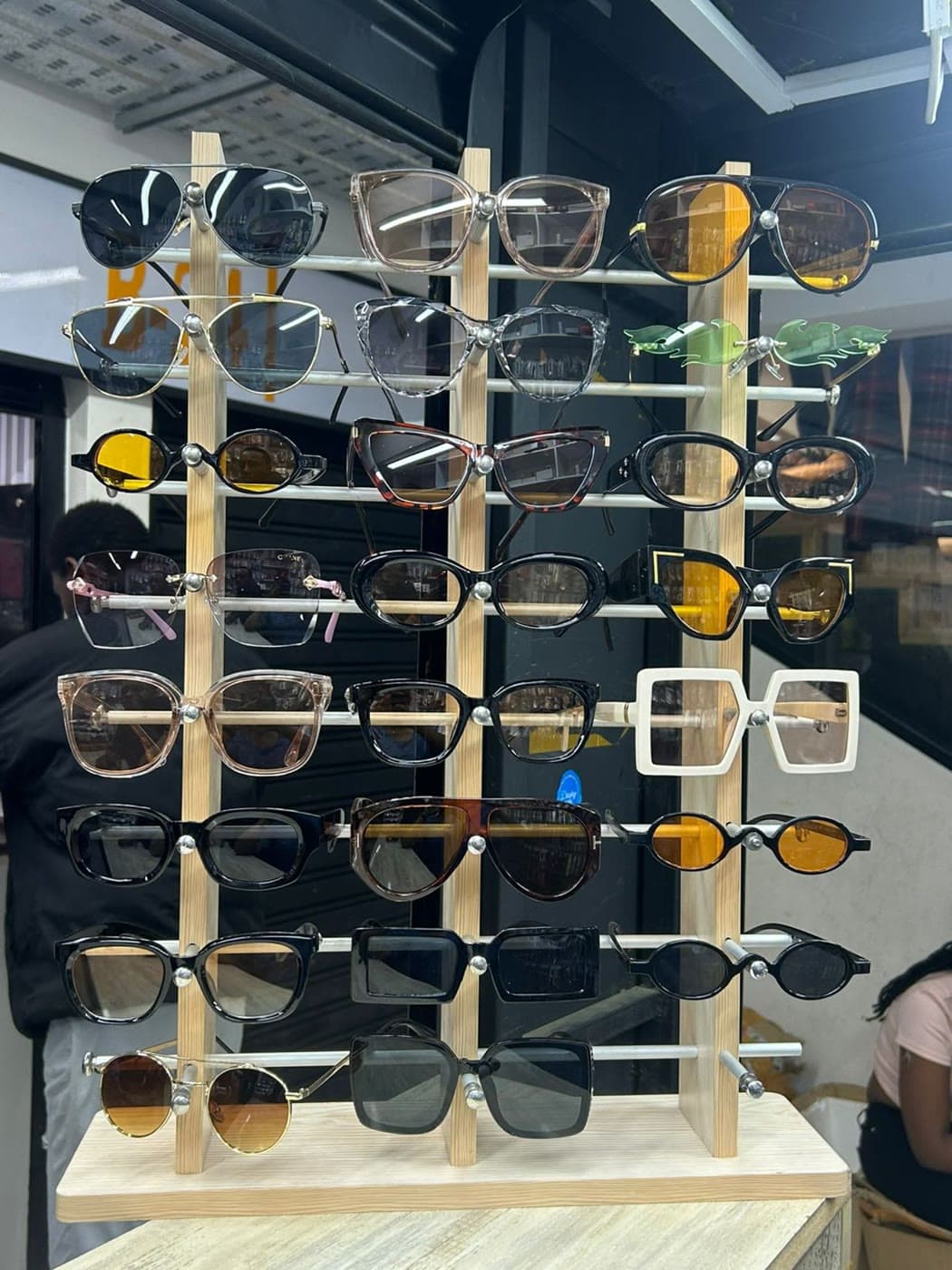 A wooden tower stacked with sunglasses on the shop counter