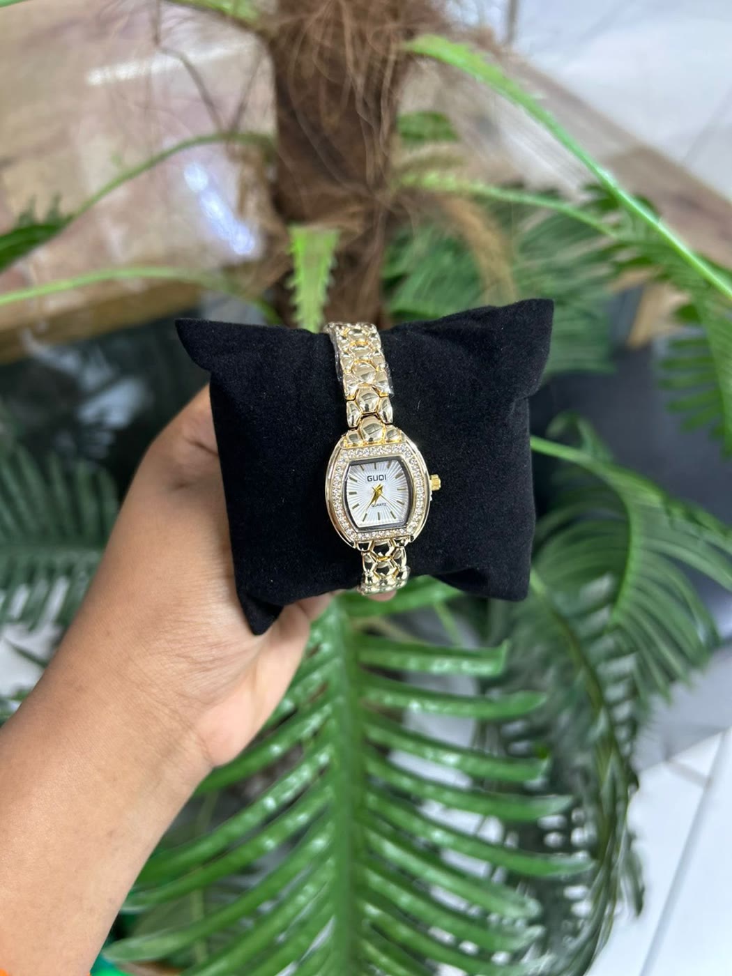 A ladies gold watch on a black velvet cushion
